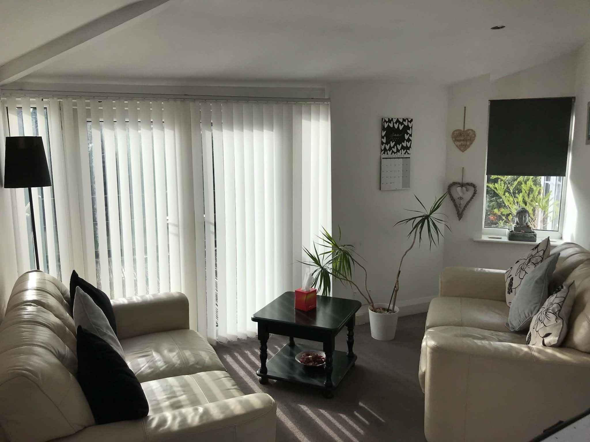 The counselling room in sunlight, with two cream sofas, a low table and a window onto the garden